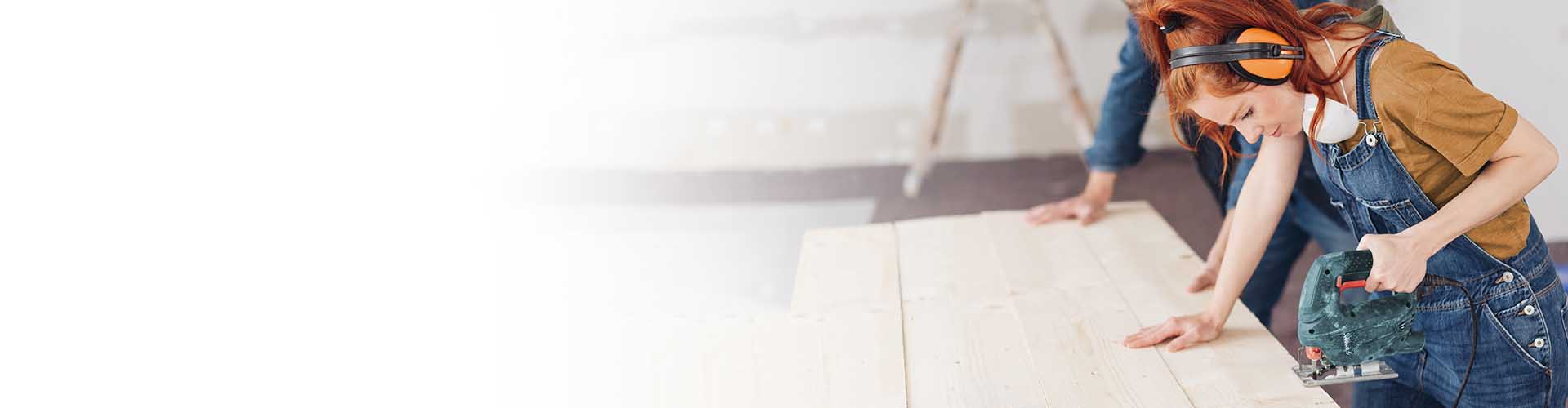 Girl wearing yellow shirt and overalls using table saw