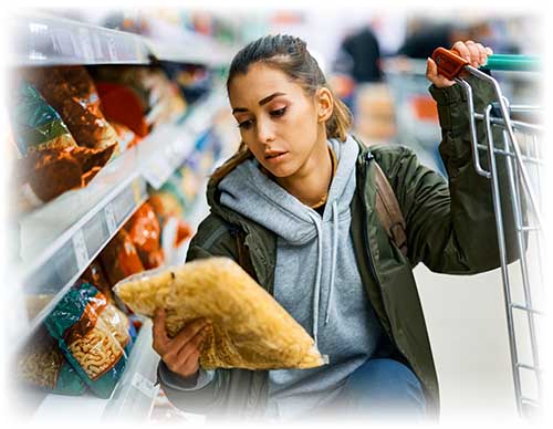 Person kneeling down looking at bag of chips. Wearing a green jacket and gray sweatshirt