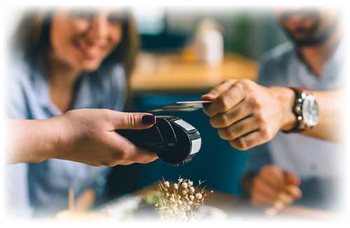 Couple sitting at table tapping their credit card to pay