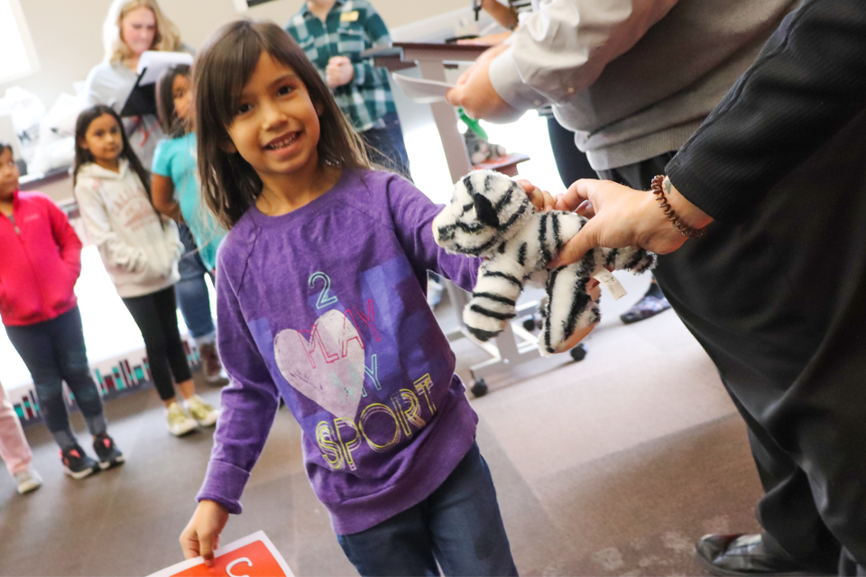 Girl is handed stuffed tiger.