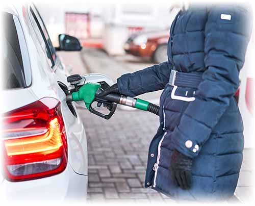 Person in blue coat pumping gas into white car