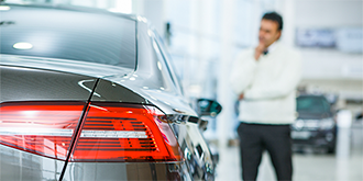 Man standing next to car in dealership