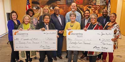 Group of Ascentra staff and Friends of MLK staff with 2 giant checks written out for $50,000 in total