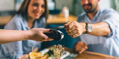 Couple sitting at table tapping their credit card to pay
