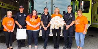 Group of Ascentra staff standing in front of yellow fire truck with firefighters ES