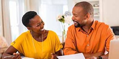 Man in orange shirt and woman in yellow shirt looking at each other smiling