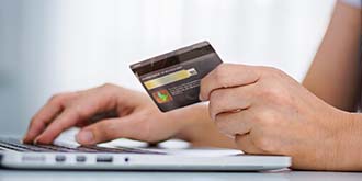 Someone holding credit card and typing on laptop