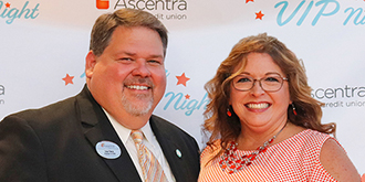 Dale and Angie Owen standing in front of Ascentra VIP night backdrop