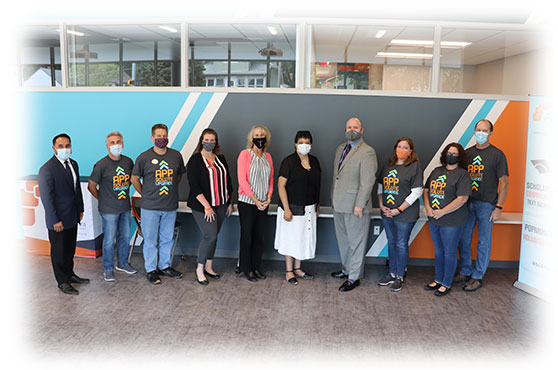 Phyllis Thede and staff of Ascentra stand in front of orange, blue, and gray wall