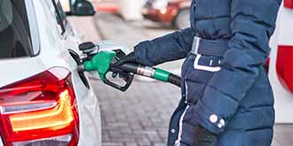 Person in blue coat pumping gas into white car