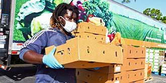 Man carrying cardboard pallet full of food