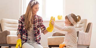 Mother and daughter high fiving. Mother wearing yellow gloves and flannel shirt