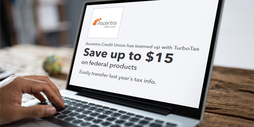Laptop screen with TurboTax coupon displayed on it. Hand resting on keyboard and laptop sitting on wooden desk
