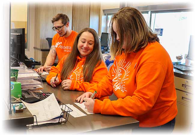 Group of ascentra team members standing around computer