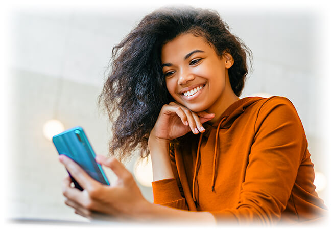 Girl wearing orange sweatshirt smiling and looking at her blue phone