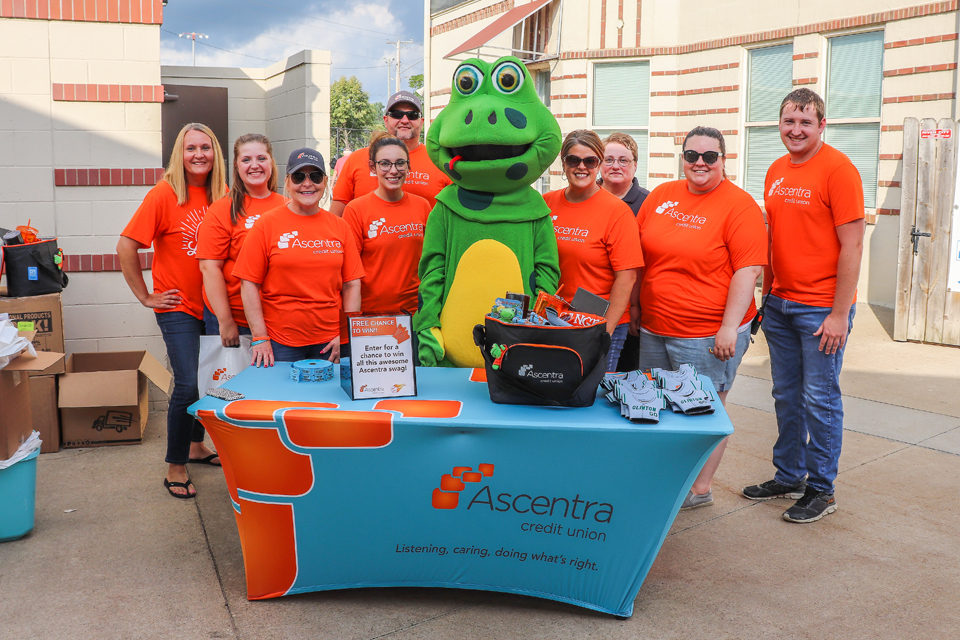 Ascentra team wearing orange shirts standing behind a blue table