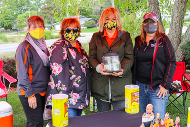 Group of ladies in masks standing behind lemonade stand
