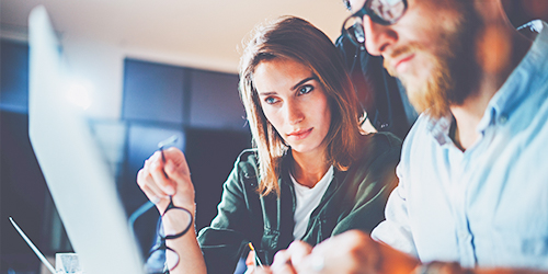 Couple wearing black glasses reviewing finances on computer 